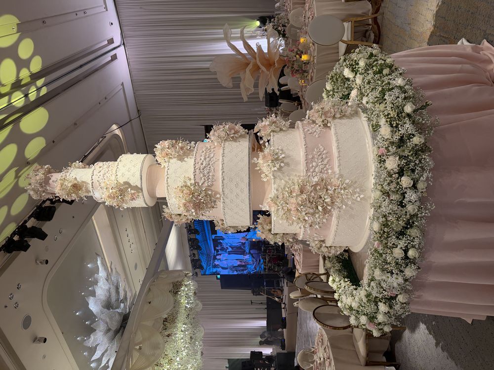 Tall wedding cake in ballroom with florals